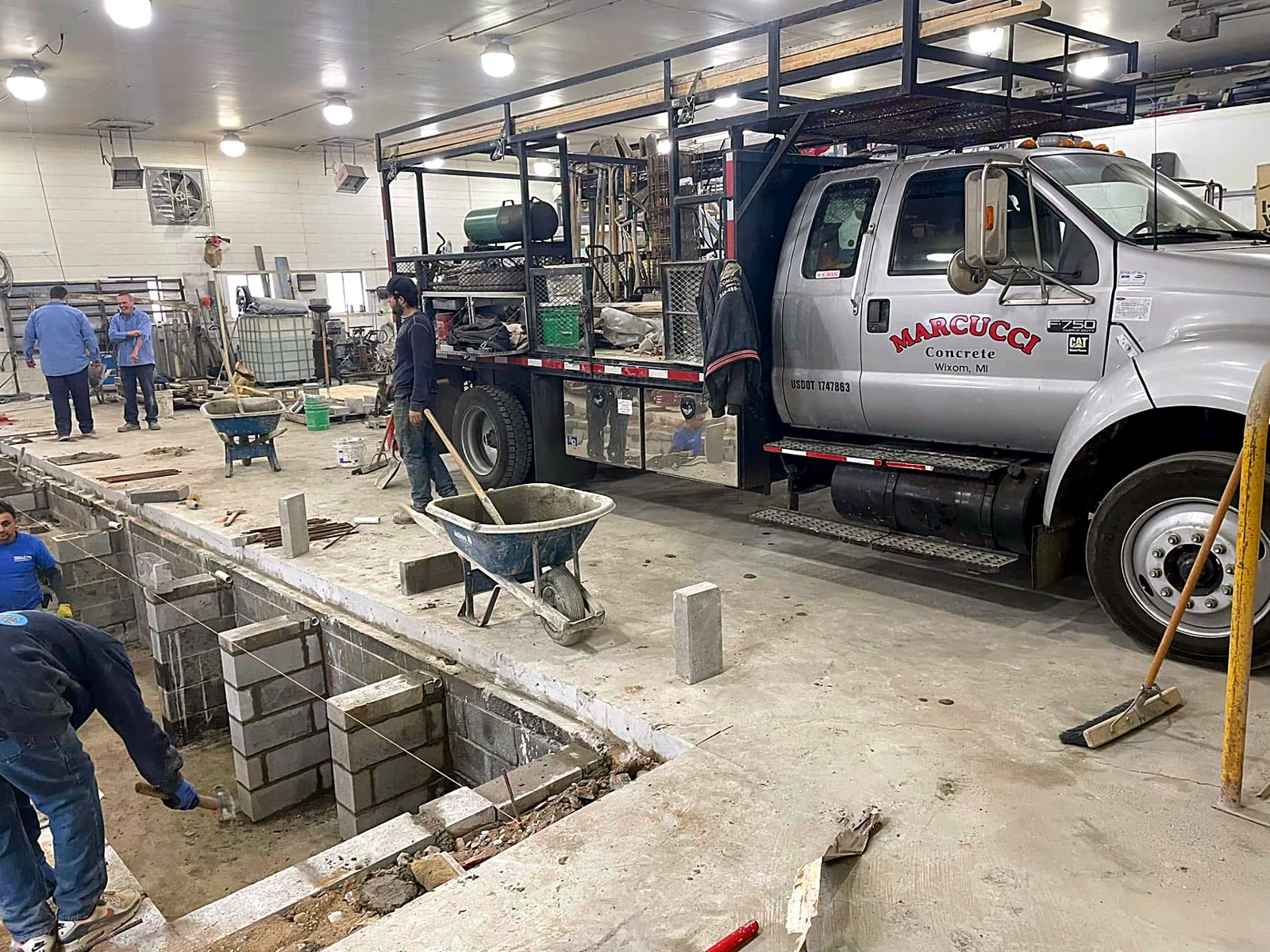 Marcucci Concrete F-750 crew truck on site setting block footings inside an auto shop for a commercial client