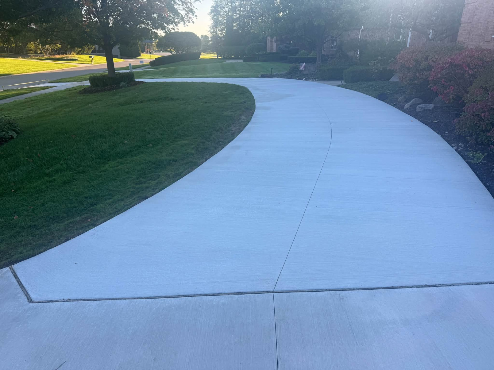 Sweeping curved concrete driveway with broom finish and tooled control joints at an Oakland County, MI home by Marcucci Concrete